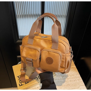 Detail of camel nylon crossbody bag with dual front pockets and adjustable strap