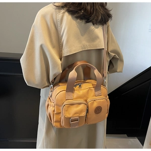 Rear view of a mustard yellow crossbody bag worn over a trench coat for size demonstration