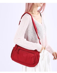 Close-up of red multi-pocket nylon shoulder bag with water-resistant fabric and zippers