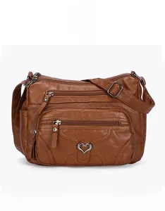 Détail frontal du sac bandoulière marron en cuir PU avec plusieurs zips et pendentif cœur