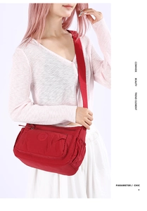 Side view of red waterproof nylon crossbody bag worn on shoulder by a female model