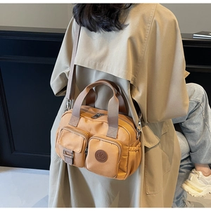 Rear view of khaki nylon crossbody bag with multi-pockets paired with a trench coat