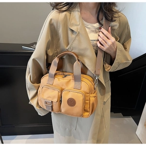 Detail of khaki water-resistant nylon crossbody bag with dual front pockets and logo