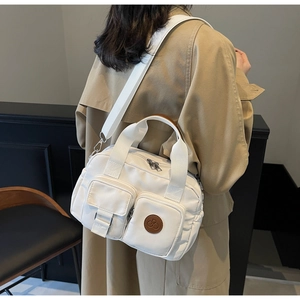 Detailed side view of white multi-pocket canvas crossbody bag with adjustable wide strap