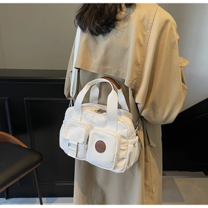 Detailed back view of a white nylon crossbody bag with multi-pockets on a model's outfit