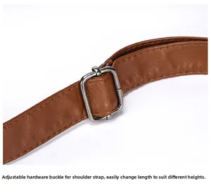 Gros plan d'une bandoulière de sac en cuir marron avec boucle en métal argenté réglable