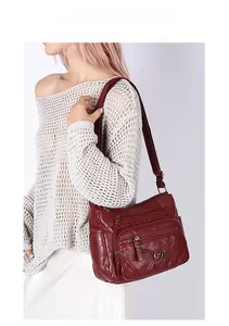 Sac bandoulière rouge foncé en cuir souple avec poches zippées et détail cœur sur mannequin