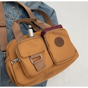Detail of caramel nylon crossbody bag with multi-pockets and bicycle logo on denim