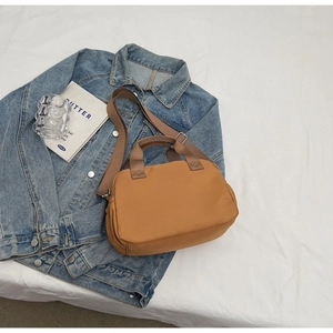 Detail view of khaki nylon tote bag on denim jacket with lifestyle accessories