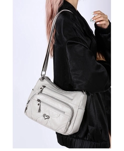 Vue détaillée d'un sac à bandoulière gris souple à poches multiples et détail de cœur