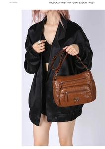 Détail d'un sac à bandoulière en cuir souple marron avec poches zippées et boucle en cœur