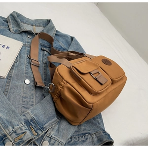 Close-up of brown nylon crossbody bag with multi-pocket design on denim jacket