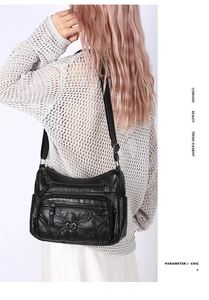 Détail du sac bandoulière en cuir noir avec boucle cœur en métal et poches zippées multiples