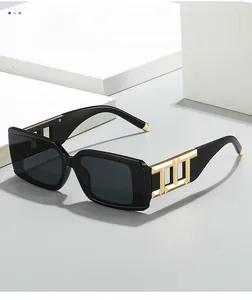 Close-up of wide black square sunglasses frame featuring distinctive gold metal geometric accents