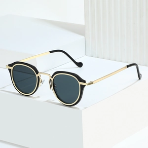 Retro oval sunglasses with gold metal frame and dark gray lenses on white pedestal