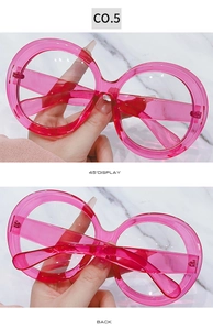 Detail view of pink oversized round sunglasses with translucent frames and 45-degree angle