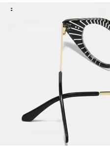 Detail of black and white striped cat-eye frame with gold metal hinge and curved legs