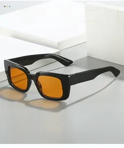 Détail de lunettes de soleil carrées noires avec verres oranges sur fond gris