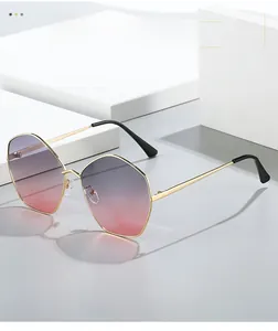 Detail of hexagonal gold metal sunglasses with purple gradient lenses on white pedestal
