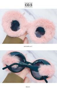 Detail of pink faux fur trim on round sunglasses with black lenses and marble background