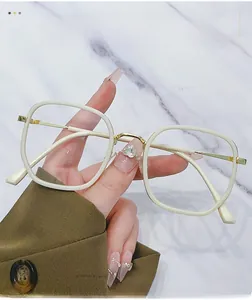 Detailed close-up of cream square glasses frame with gold metal temples and bridge