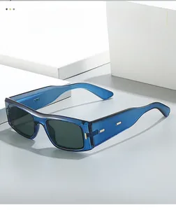 Détail de lunettes de soleil carrées bleu transparent avec accents métalliques dorés