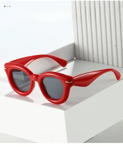 Detail of red oversized puffy frame sunglasses with dark grey lenses on white platform
