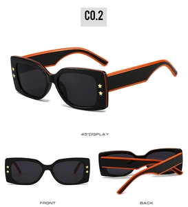 Detail view of square black sunglasses with orange contrast and gold star accents
