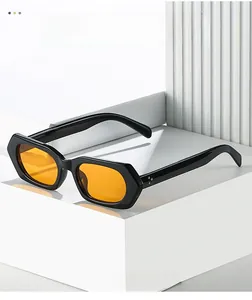 Detail of black hexagonal sunglasses with orange lenses and silver rivets on white pillars