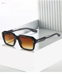 Close-up of black square sunglasses featuring star-shaped gold rivets and gradient brown lenses