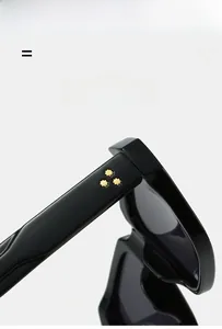 Detail of black sunglasses arm featuring three golden star-shaped rivets and sleek texture