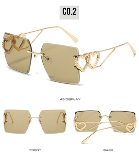 Détail de lunettes de soleil carrées sans monture avec verres thé et charnière cœur doré