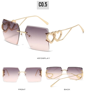 Détail de lunettes de soleil cœur sans monture avec branches dorées et verres dégradés