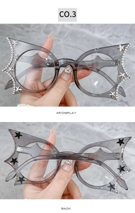 Detail of bat-wing shaped transparent gray glasses with sparkling rhinestones and stars