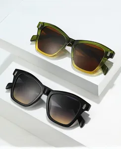 Close-up of olive green and black square sunglasses with metallic rivets and gradient lenses