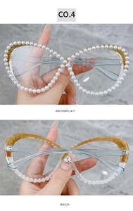 Detailed close-up of large butterfly glasses frame encrusted with white pearls and crystals