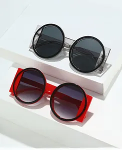 Détail de lunettes rondes avec montures épaisses rouges et gris transparent sur socle