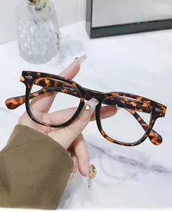 Detail of tortoise shell round frames with blue light blocking lenses held by hand