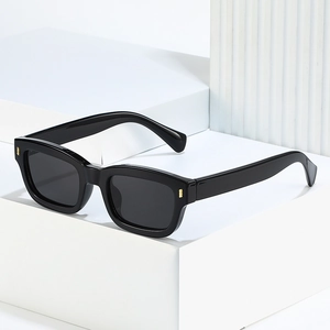 Modern black square sunglasses with gold metal accents on white geometric props