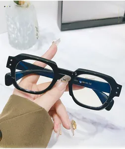 Detail of vintage thick black acetate eyewear frame held over a marble background