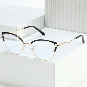 Cat eye black and gold glasses frame with wavy metal temples on a white podium