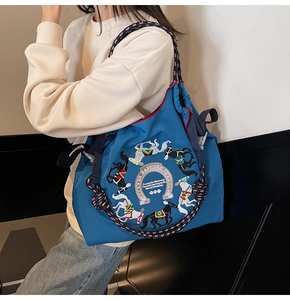 Dettaglio della borsa shopper blu in tessuto oxford con ricamo a cavallo e manici intrecciati