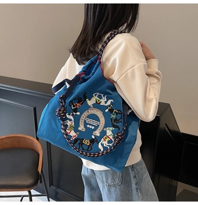 Dettaglio della borsa tote in nylon blu con ricamo di cavallo e manici in corda intrecciata