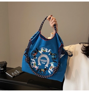Dettaglio della borsa tote in tela blu con ricamo a cavallo e manici in tessuto ritorto