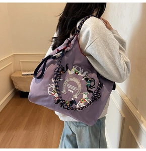Dettaglio della borsa tote viola con ricamo di cavallo e manico in corda blu e gialla