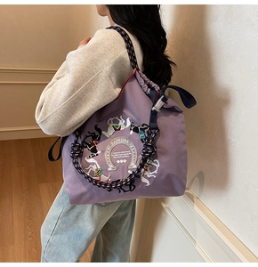 Vista laterale dettagliata della borsa tote viola con ricamo e tracolla in corda intrecciata