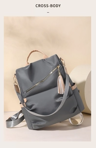 Detail of waterproof dark grey backpack featuring brown leather trim and tassel accent
