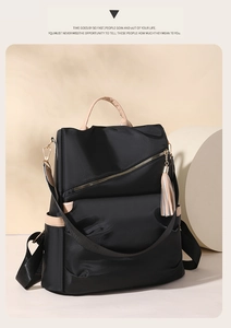 Detail of minimalist black nylon backpack with beige leather trim and tassel charm
