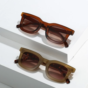 Minimalist square frame sunglasses in amber brown and olive green on geometric blocks