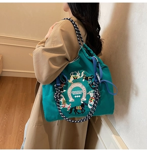 Dettaglio del ricamo a cavallo su borsa tote in nylon verde con manici intrecciati